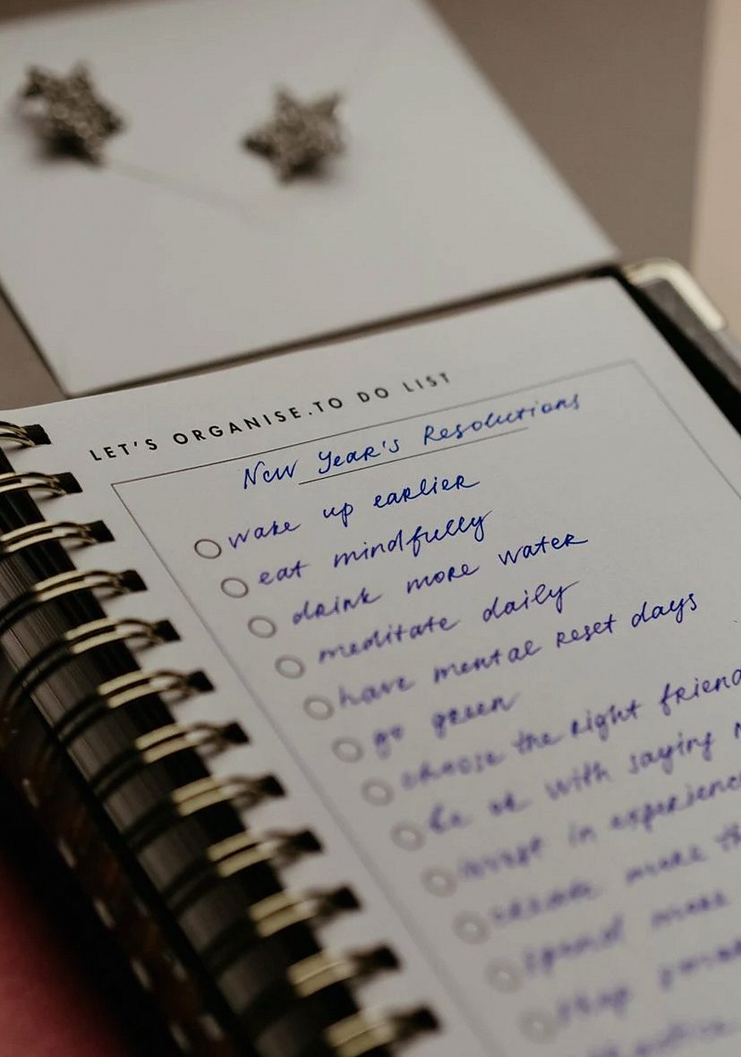 Close-up of a notebook with handwritten New Year's resolutions, organized neatly for planning.